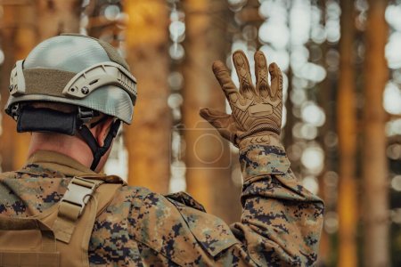 Photo for Modern warfare soldier officer is showing tactical hand signals to silently give orders and alers for squad team forest enviroment. - Royalty Free Image