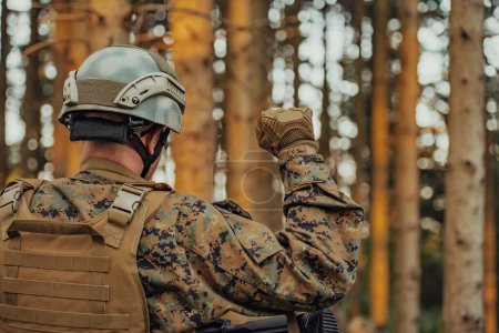 moderner Soldat zeigt taktische Handsignale, um lautlos Befehle zu erteilen und die Umgebung des Truppenteams zu erforschen.