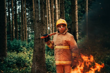 Téléchargez les photos : Pompier au travail. Pompier dans des zones forestières dangereuses entourées de feux violents. Concept du travail du service d'incendie. H - en image libre de droit