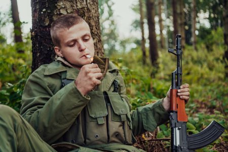 Photo for Terrorist have a break and smoke cigarette in forest during battle. - Royalty Free Image