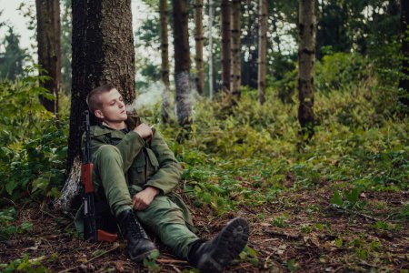 Téléchargez les photos : Terroriste ont une pause et fumer la cigarette dans la forêt pendant la bataille. - en image libre de droit