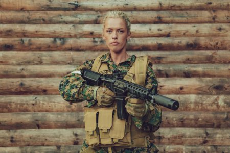 Photo for Woman soldier ready for battle wearing protective military gear and weapon. - Royalty Free Image