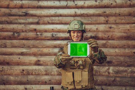 Foto de Mujer soldado usando tableta ordenador contra pared de madera vieja en el campo. - Imagen libre de derechos