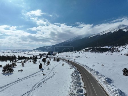 Foto de Avión aéreo, dron disparado sobre árboles sin hojas, por encima de una montaña nevada y hermosos picos de montañas nevadas. El desierto de invierno, en un día soleado. Imágenes de alta calidad 4k - Imagen libre de derechos