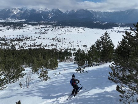 Foto de Cinematic Aerial downhill freeride esquí en nieve fresca y profunda con un paisaje de montaña increíble. Atletas freeride mostrando giros de esquí de pista con una vista panorámica impresionante. Imágenes de alta calidad 4k - Imagen libre de derechos