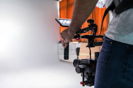 Téléchargez les photos : Le caméraman en studio utilisant une caméra professionnelle avec un stabilisateur. - en image libre de droit
