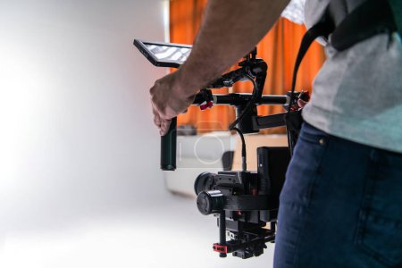 Foto de El camarógrafo en el estudio usando una cámara profesional con un estabilizador. - Imagen libre de derechos