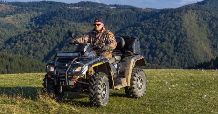 Photo for A man driving a quad ATV motorcycle through beautiful meadow landscapes. High quality photo - Royalty Free Image
