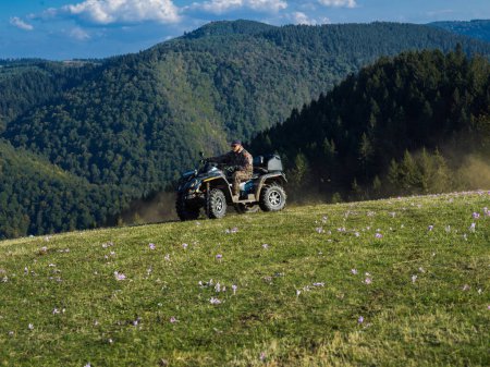 Foto de Un hombre conduciendo una motocicleta quad ATV a través de hermosos paisajes del prado. Foto de alta calidad - Imagen libre de derechos