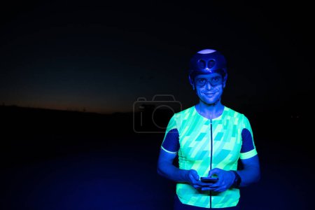 Foto de Un triatleta que usa un smartphone mientras se toma un descanso de un duro entrenamiento nocturno en bicicleta. Foto de alta calidad - Imagen libre de derechos