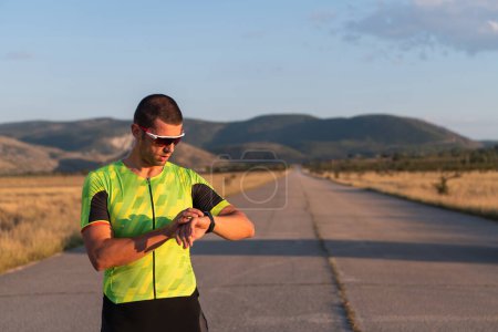 Téléchargez les photos : Le triathlète vérifie ses statistiques d'entraînement sur une smartwatch, en analysant ses performances et ses progrès. Avec dévouement, discipline et persévérance, il s'efforce d'améliorer ses capacités physiques et - en image libre de droit