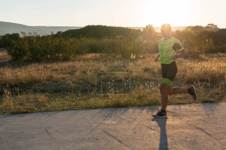 Téléchargez les photos : Triathlète en équipement professionnel qui court tôt le matin, se prépare pour un marathon, se consacre au sport et est prêt à relever les défis d'un marathon - en image libre de droit