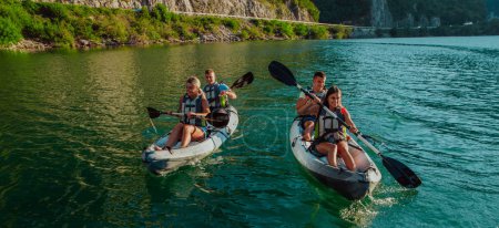 Foto de Un grupo de amigos disfrutando de la diversión y el kayak explorando el río tranquilo, el bosque circundante y los grandes cañones naturales del río durante una idílica puesta de sol - Imagen libre de derechos