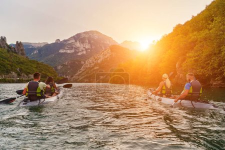Téléchargez les photos : Un groupe d'amis profitant du plaisir et du kayak explorant la rivière calme, la forêt environnante et les grands canyons naturels de la rivière lors d'un coucher de soleil idyllique - en image libre de droit