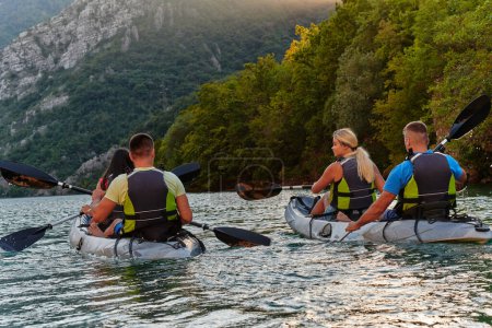 Foto de Un grupo de amigos disfrutando de divertirse y hacer kayak mientras exploran el río tranquilo, el bosque circundante y los grandes cañones naturales del río.. - Imagen libre de derechos