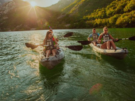 Photo for A group of friends enjoying fun and kayaking exploring the calm river, surrounding forest and large natural river canyons during an idyllic sunset - Royalty Free Image