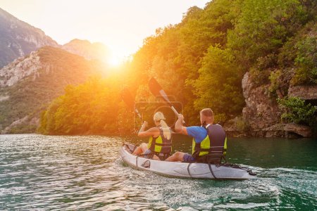Foto de Un grupo de amigos disfrutando de la diversión y el kayak explorando el río tranquilo, el bosque circundante y los grandes cañones naturales del río durante una idílica puesta de sol - Imagen libre de derechos