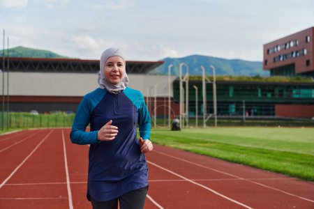 Téléchargez les photos : Une femme musulmane dans un burqa sport vêtements musulmans courir sur un parcours de marathon et se préparer pour les prochaines compétitions. - en image libre de droit