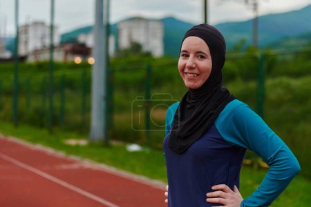 Téléchargez les photos : Une femme musulmane avec une burqa, une sportive islamique se reposant après une séance d'entraînement vigoureuse sur le parcours du marathon. Une femme hijab se prépare pour une compétition de marathon. - en image libre de droit