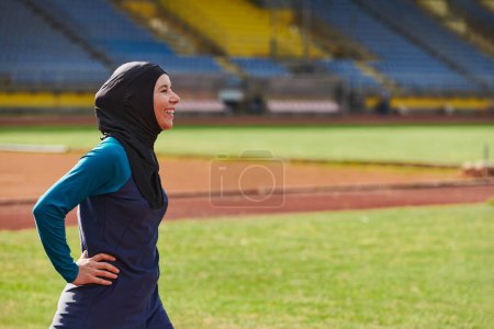 Foto de Una mujer musulmana con una burka, una deportista islámica descansando después de una vigorosa sesión de entrenamiento en el curso de maratón. Una mujer hiyab se está preparando para una competencia maratónica. - Imagen libre de derechos