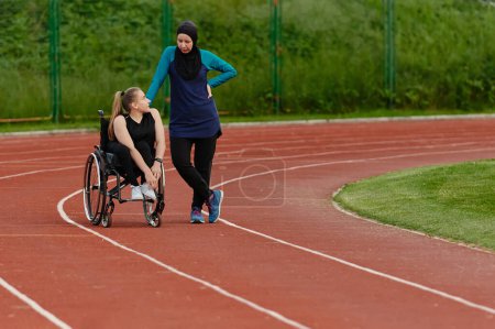 Foto de Una mujer musulmana con un burka descansando con una mujer con discapacidad después de una dura sesión de entrenamiento en el curso de maratón. - Imagen libre de derechos