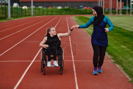 Téléchargez les photos : Une musulmane portant une burqa soutient son amie handicapée dans un fauteuil roulant alors qu'elle s'entraîne ensemble sur un parcours de marathon - en image libre de droit