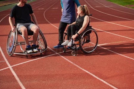 Foto de Una mujer con una discapacidad en silla de ruedas hablando después de entrenar con una mujer que lleva un hijab y un hombre en silla de ruedas. - Imagen libre de derechos