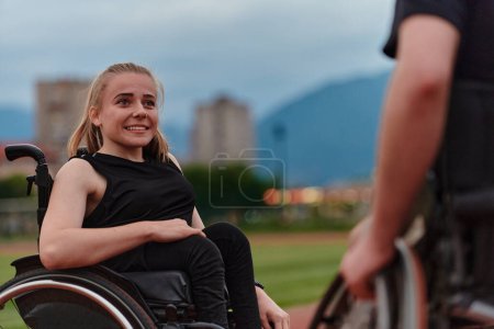 Téléchargez les photos : Une femme handicapée en fauteuil roulant discute avec un ami après s'être entraînée sur le parcours du marathon. - en image libre de droit