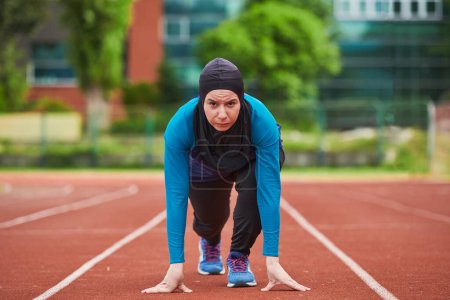Foto de Mujer musulmana en burka con ropa deportiva musulmana en pose inicial para correr. Foto de alta calidad - Imagen libre de derechos