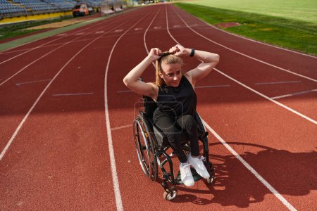Foto de Una mujer con discapacidad en silla de ruedas que muestra dedicación y fuerza al mostrar sus músculos. - Imagen libre de derechos