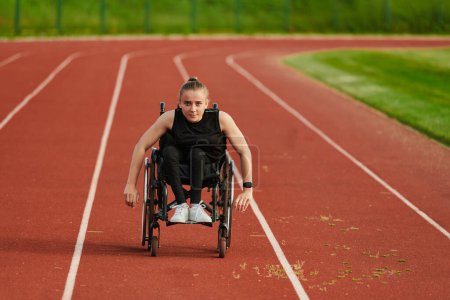 Foto de Una mujer con discapacidad que conduce una silla de ruedas en una pista mientras se prepara para los Juegos Paralímpicos. - Imagen libre de derechos