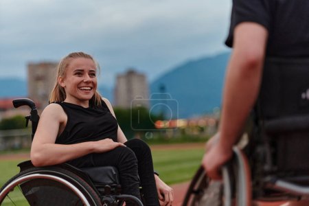 Foto de Una mujer con discapacidad en silla de ruedas hablando con un amigo después de entrenar en el curso de maratón. - Imagen libre de derechos