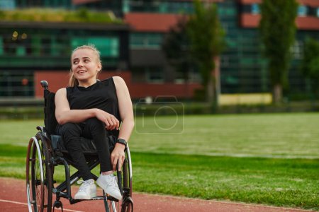 Photo for A smiling woman with disablitiy sitting in a wheelchair and resting on the marathon track after training. - Royalty Free Image