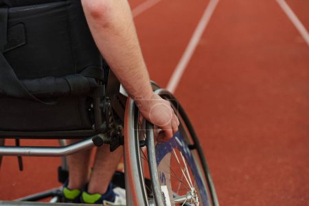 Téléchargez les photos : Photo rapprochée d'une personne handicapée en fauteuil roulant s'entraînant inlassablement sur la piste en préparation des Jeux paralympiques. - en image libre de droit