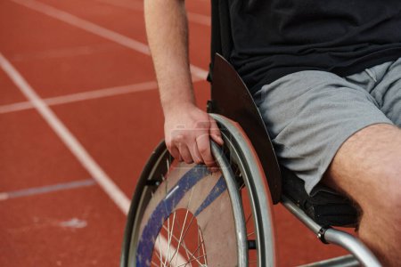 Téléchargez les photos : Photo rapprochée d'une personne handicapée en fauteuil roulant s'entraînant inlassablement sur la piste en préparation des Jeux paralympiques. - en image libre de droit