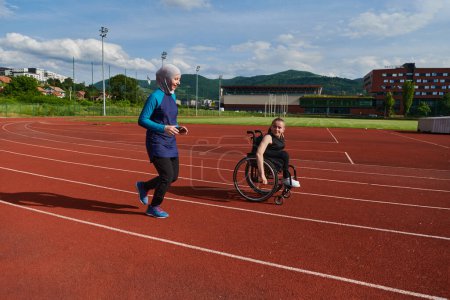 Téléchargez les photos : Une musulmane dans une burqa en train de courir avec une femme en fauteuil roulant sur le parcours du marathon, se préparant pour de futures compétitions - en image libre de droit