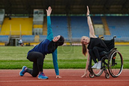 Téléchargez les photos : Deux femmes fortes et inspirantes, l'une musulmane portant une burka et l'autre en fauteuil roulant étirant et préparant leur corps pour une course de marathon sur la piste. - en image libre de droit