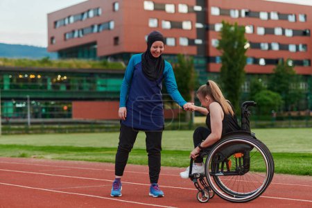 Photo for A Muslim woman wearing a burqa supports her friend with disability in a wheelchair as they train together on a marathon course - Royalty Free Image
