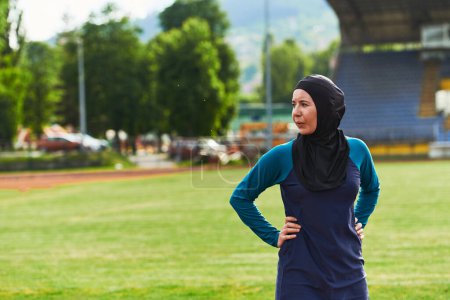 Téléchargez les photos : Une femme musulmane avec une burqa, une sportive islamique se reposant après une séance d'entraînement vigoureuse sur le parcours du marathon. Une femme hijab se prépare pour une compétition de marathon. - en image libre de droit