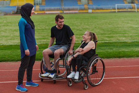 Photo for A woman with a disability in a wheelchair talking after training with a woman wearing a hijab and a man in a wheelchair. - Royalty Free Image