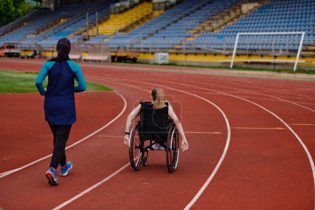 Photo for A Muslim woman in a burqa running together with a woman in a wheelchair on the marathon course, preparing for future competitions - Royalty Free Image