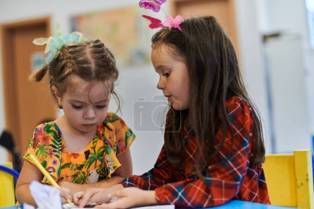 Foto de Niños creativos sentados en una institución preescolar, dibujan y se divierten mientras reciben una educación. Foto de alta calidad - Imagen libre de derechos