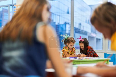 Foto de Niños creativos durante una clase de arte en una guardería o en el aula de la escuela primaria dibujando con una maestra - Imagen libre de derechos