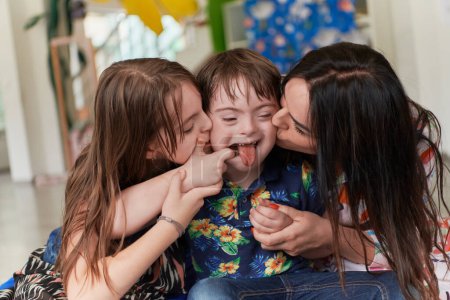 Photo for A girl and a woman hug a child with down syndrome in a modern preschool institution. High quality photo - Royalty Free Image