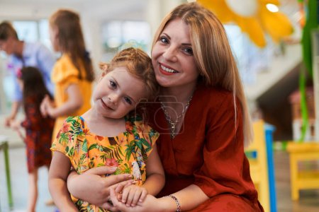 Photo for A cute little girl kissing and hugs her mother in preschool. High quality photo - Royalty Free Image