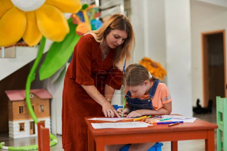 Photo for Creative kids during an art class in a daycare center or elementary school classroom drawing with female teacher. High quality photo - Royalty Free Image