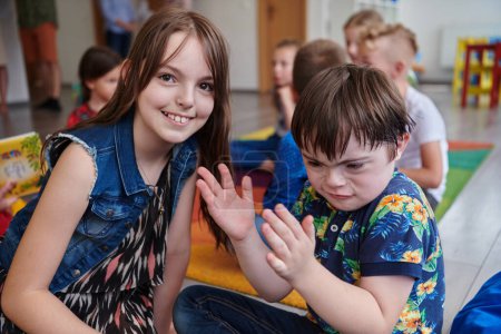 Foto de Una niña y un niño con síndrome de Downs en los brazos del otro pasan tiempo juntos en una institución preescolar. - Imagen libre de derechos