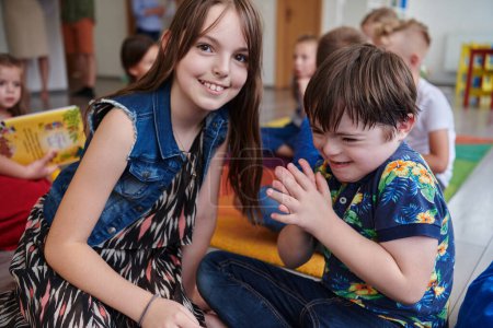 Foto de Una niña y un niño con síndrome de Downs en los brazos del otro pasan tiempo juntos en una institución preescolar. - Imagen libre de derechos