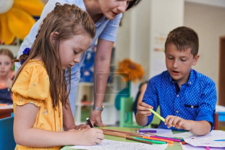 Téléchargez les photos : Enfants créatifs lors d'un cours d'art dans une garderie ou une école élémentaire dessin en classe avec une enseignante - en image libre de droit