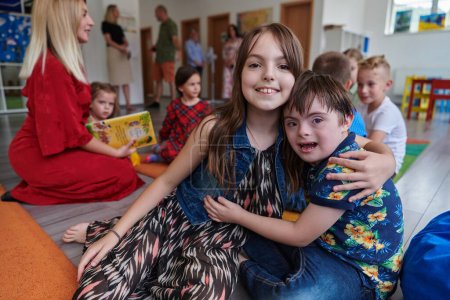 Photo for A girl and a boy with Downs syndrome in each others arms spend time together in a preschool institution. - Royalty Free Image